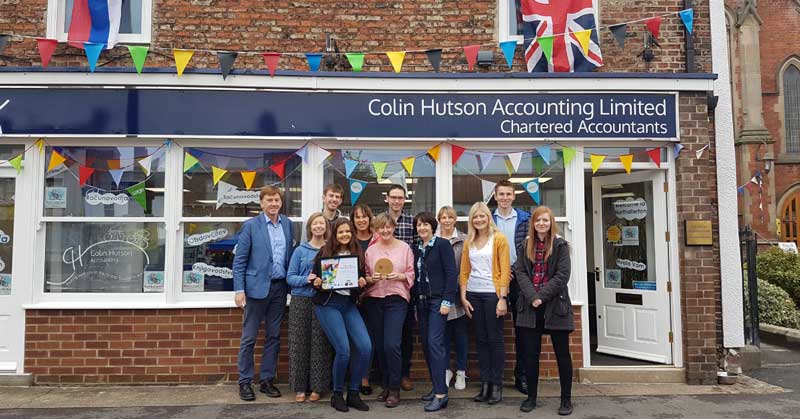 Group photo of employees standing in front of the window display with an award