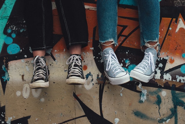 person in blue denim jeans wearing black and white converse all star high top trainers