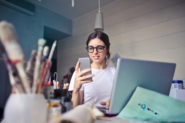 woman in white shirt using phone at work