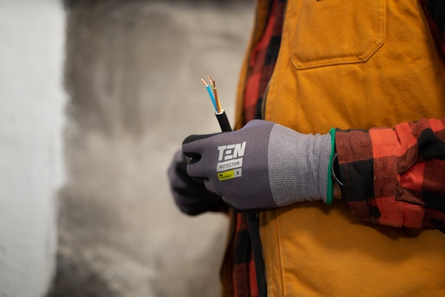 electrician with work gloves holding a wire