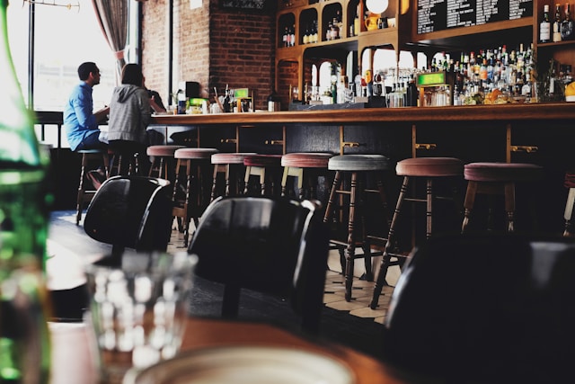 two people sitting on bar stools in a pub