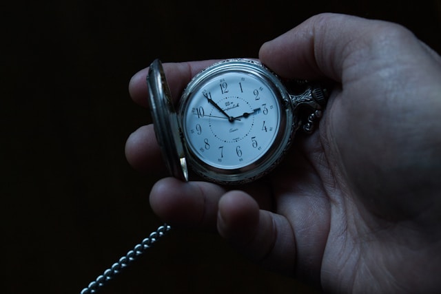 hand holding a silver pocket watch