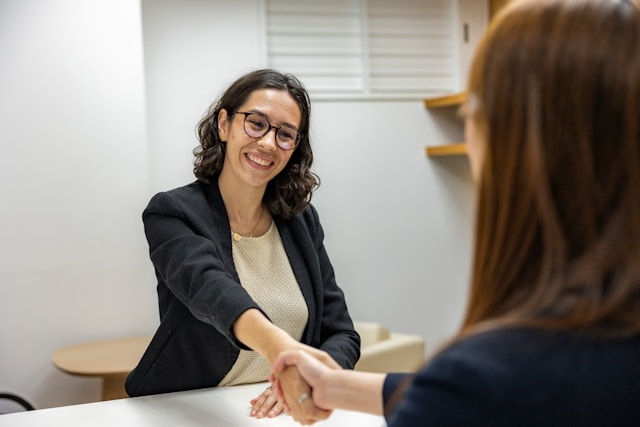woman shaking hands with another woman sitting at a table
